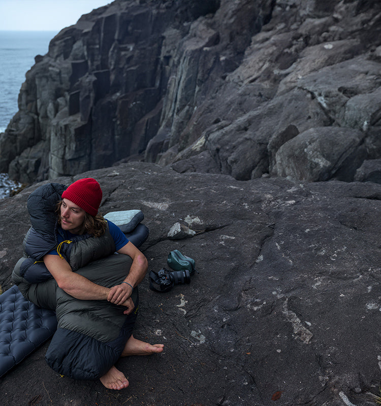 Man sits on his ultralight Sleep Systems while backpacking 